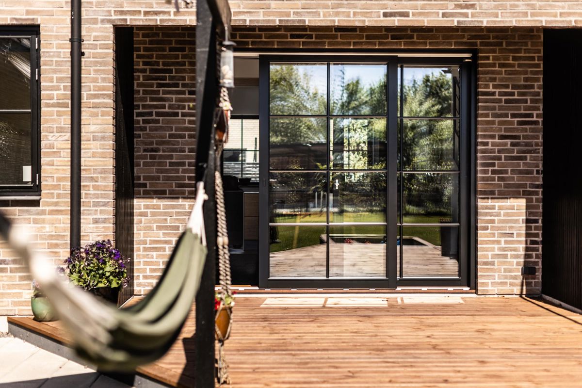 Sort hæveskydedør på flot terrasse i nybyggeri stil Sort hæveskydedør på flot terrasse i nybyggeri stil